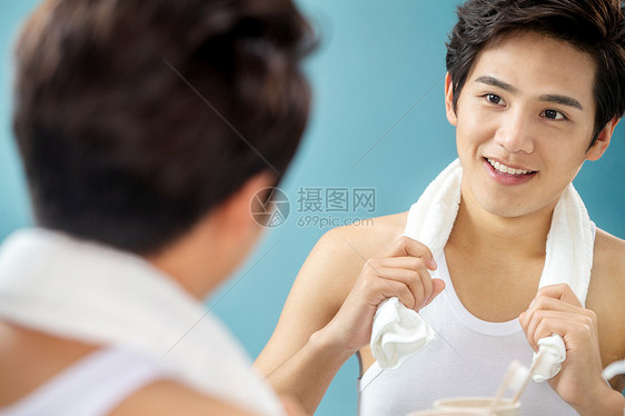 反射清新英俊年轻男人拿着毛巾照镜子图片