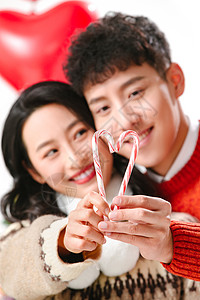 愉悦两个人毛衣快乐的青年情侣拿着拐杖糖高清图片