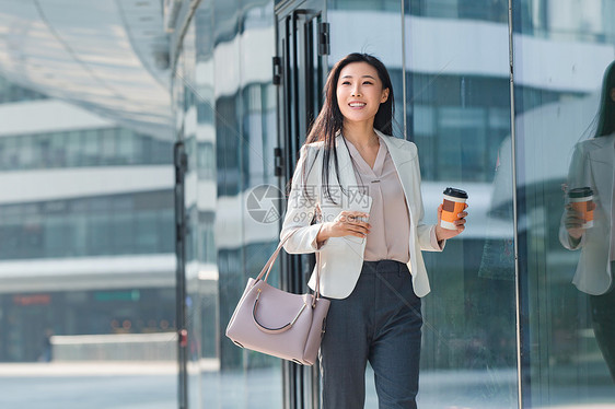 信心正装望京soho拿着咖啡杯步行的商务女图片