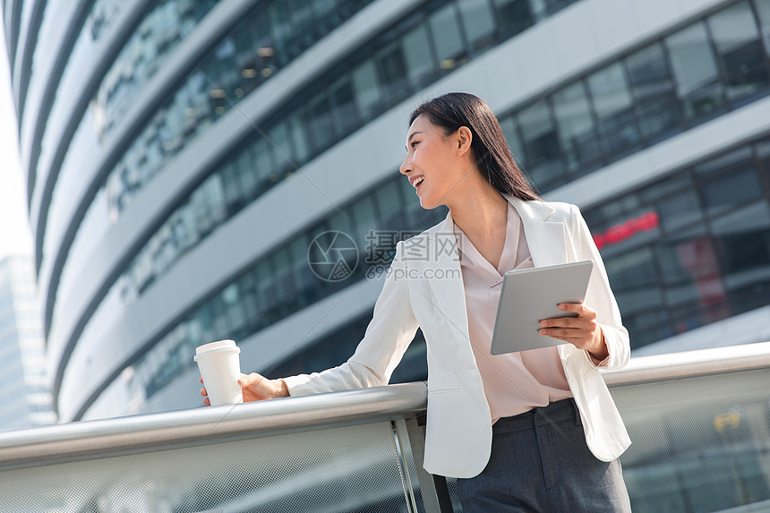 精力东方人摄影拿着平板电站在户外的商务女士图片