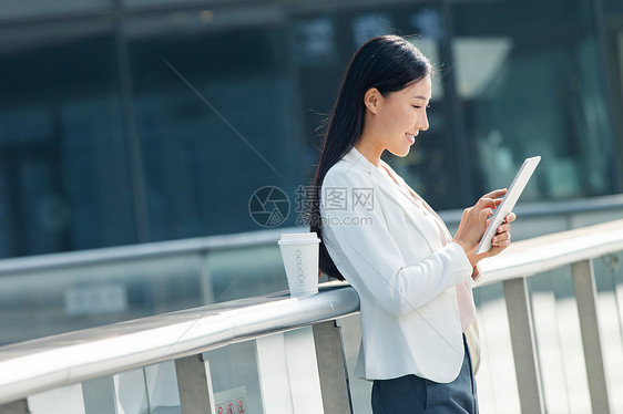 拿着平板电脑站在户外的商务女士图片