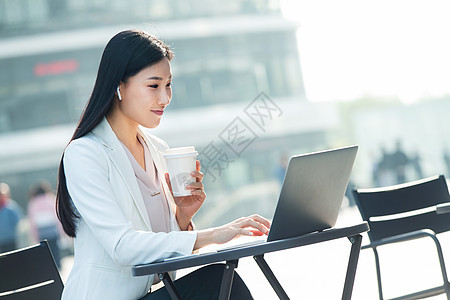 青年人一次杯子人商务女士坐在户外使用笔记本电脑图片