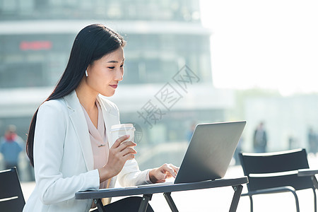 金融区白领女商人商务女士坐在户外使用笔记本电脑图片