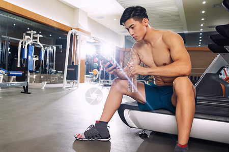 青年男人在健身房里喝水图片