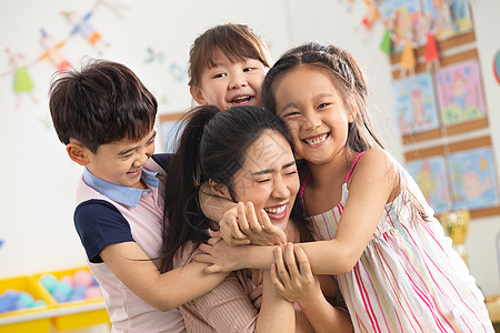 给老师拥抱高兴的纯洁团队幼儿园老师和小朋友们拥抱在一起背景