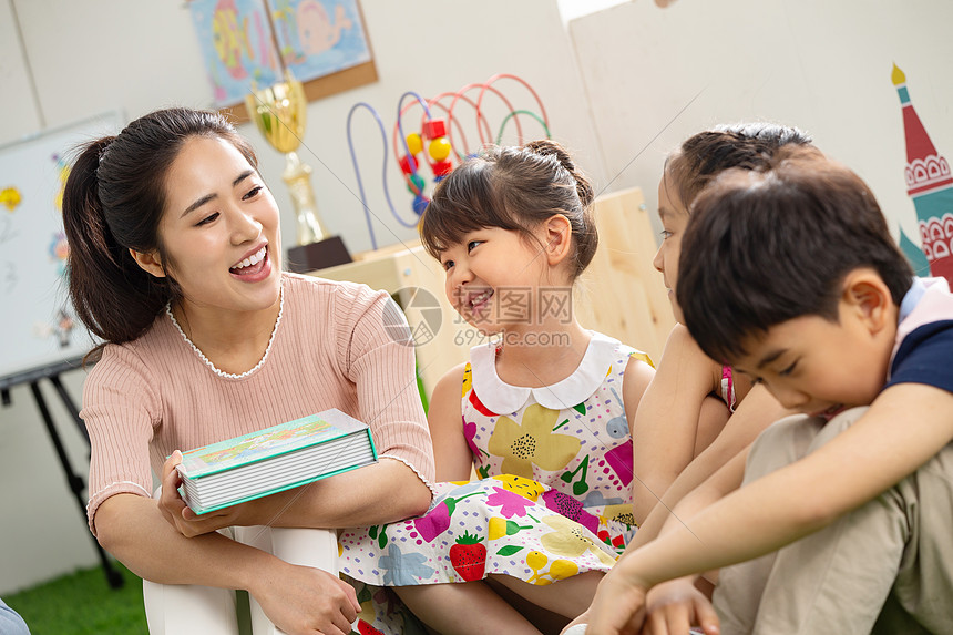 青年人同学女孩幼儿园老师给小朋友们讲故事图片