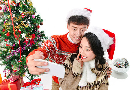 圣诞树浪漫青年情侣用手机照相图片