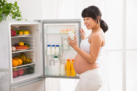 身体保养东亚露出肚子孕妇打开冰箱拿牛奶图片