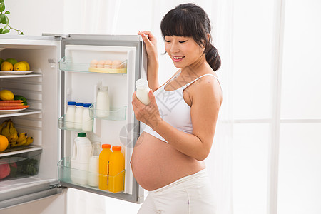 漂亮妈妈喂奶瓶东方人住宅房间橙汁孕妇打开冰箱拿牛奶背景