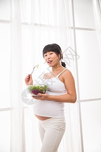 健康的幸福的孕妇吃蔬菜沙拉图片