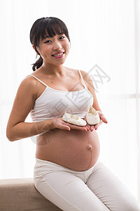 产妇婴儿幸福的孕妇手拿婴儿小鞋子背景