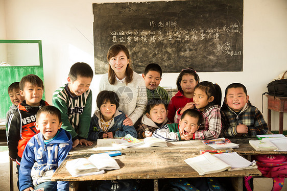 东亚人微笑的乡村女教师和小学生在教室里图片