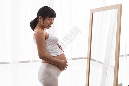 青年女人轻松期待孕妇照镜子图片
