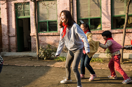 可爱的团队志愿者乡村教师和小学生在学校里做游戏图片