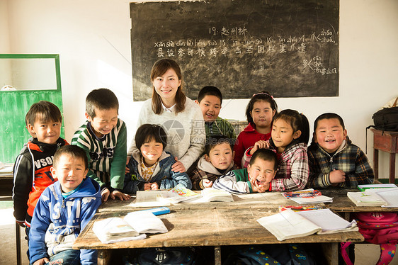 团结指导教师东方人乡村女教师和小学生在教室里图片