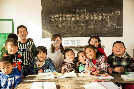 快乐援助微笑的乡村女教师和小学生在教室里图片