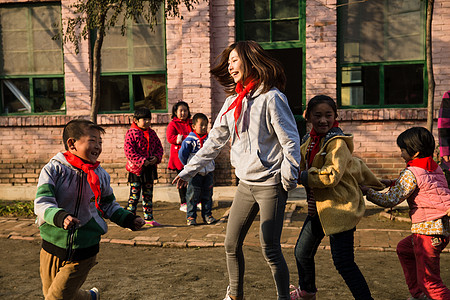 校园抓白昼乡村教师和小学生在学校里做游戏高清图片