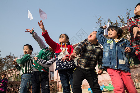 教育建筑团结水平构图乡村小学生在学校放纸飞机图片