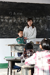 指导学龄儿童女生乡村女教师和小学生在教室里图片