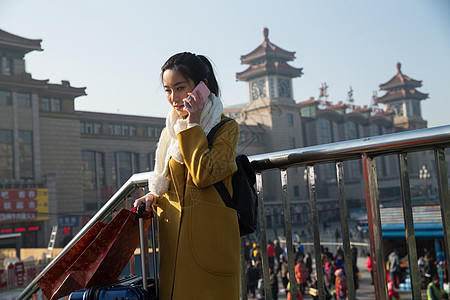 手机旅行拿着青年女人在站前广场图片