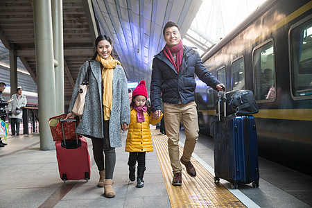 表现积极东方人厚衣服幸福家庭在车站月台背景图片
