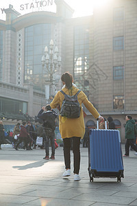 旅行箱拿着旅游青年女人在站前广场图片