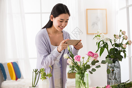 青年女人给鲜花拍照图片