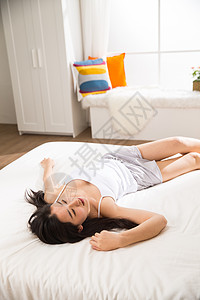 早晨亚洲放松青年女人在卧室的床上高清图片
