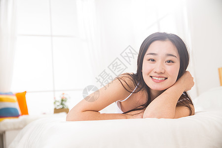 早晨微笑纯洁青年女人趴在床上图片