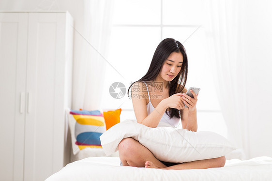 舒适吊带彩色图片青年女人在卧室用手机图片