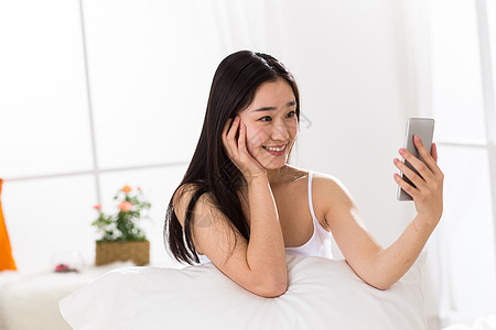 床上用品智能手机床青年女人在卧室自拍图片