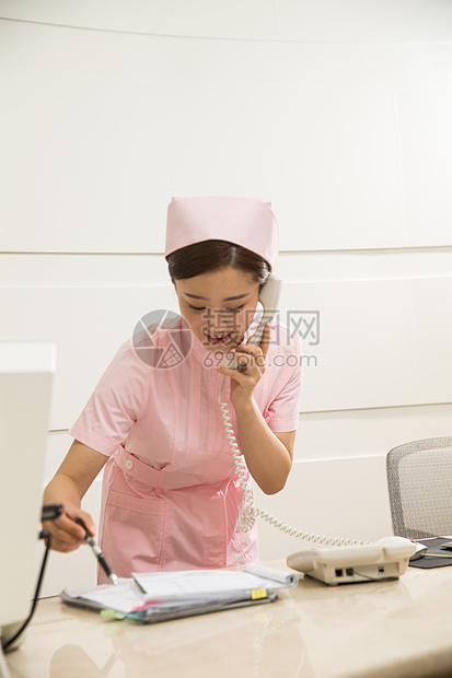 年轻女护士在接待处接电话图片