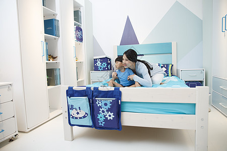 单亲家庭床上用品住宅内部可爱的小男孩和妈妈在卧室玩耍图片