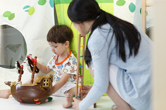 漂亮的放松柔和可爱的小男孩和指导教师在游戏室玩耍图片