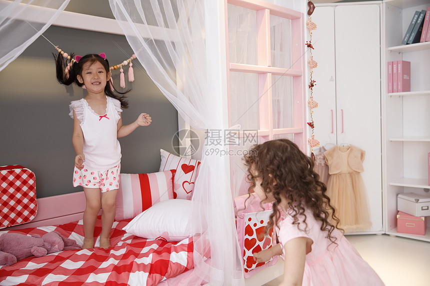 家居卷发享乐可爱的小女孩在卧室玩耍图片