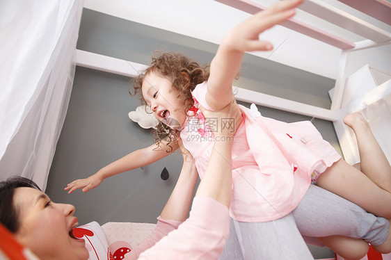 表现积极生长女儿可爱的小女孩和妈妈在卧室玩耍图片