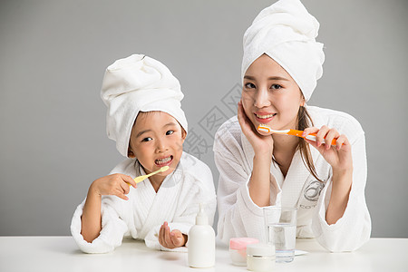 浴室温馨满意微笑穿着浴袍的母女刷牙背景