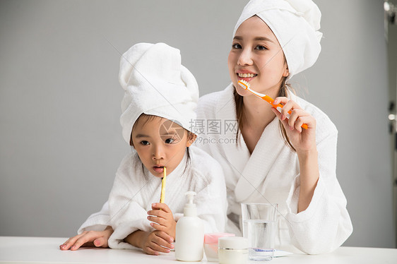 20多岁快乐活力穿着浴袍的母女刷牙图片