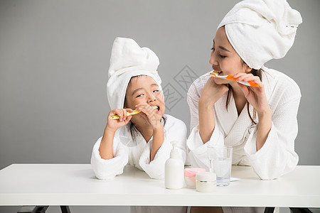 亲吻母亲女儿放松玻璃杯户内穿着浴袍的母女刷牙背景