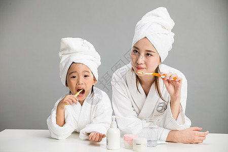 天真休闲装青年人穿着浴袍的母女刷牙高清图片