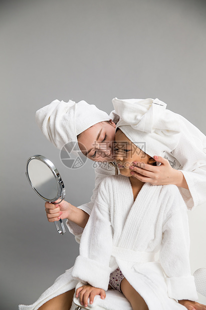 乐趣亲情拿着穿着浴袍的母女照镜子图片