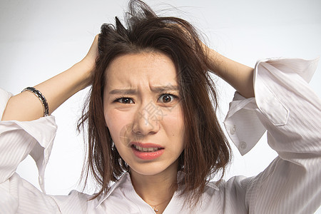 挫败皱眉头抓面部表情痛苦的青年女人背景图片