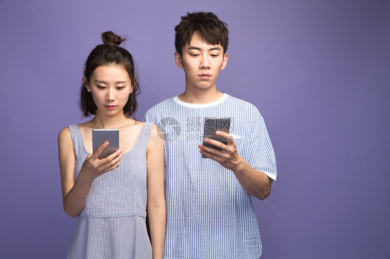 专心沟通男各自玩手机的青年情侣图片