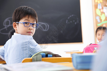 书桌学习小学男生在教室里回头看背景