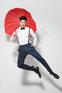 青年男人拿着心形红雨伞跳跃图片