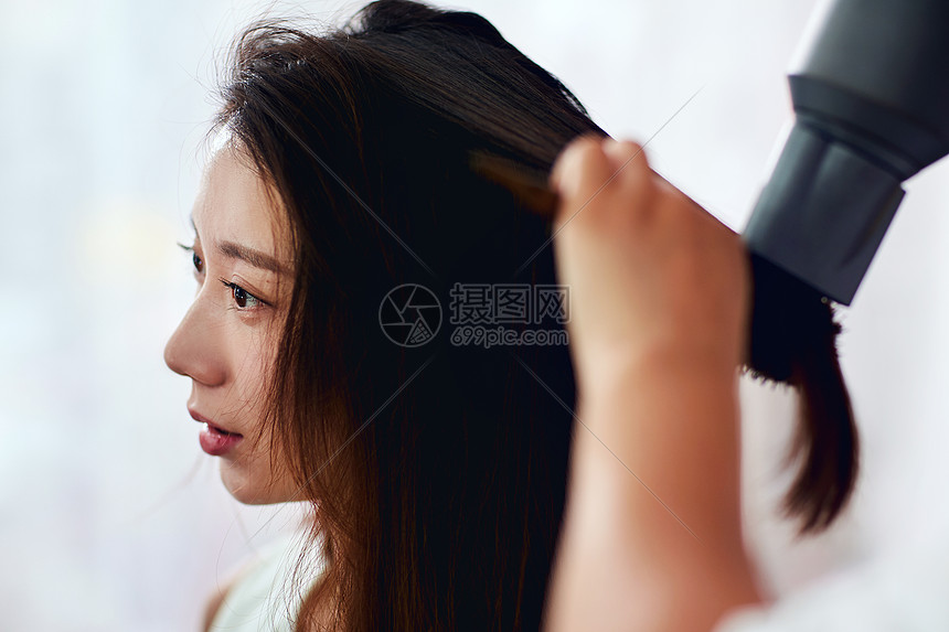 身体关注半身像造型师年轻美女在理发店里做头发