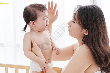 年轻妈妈抱着哭着的宝宝图片