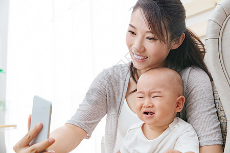 母婴亚洲人哭年轻妈妈和宝宝用手机照相背景图片