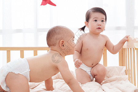 住宅内部亚洲人友谊两个可爱宝宝坐在床上玩耍图片