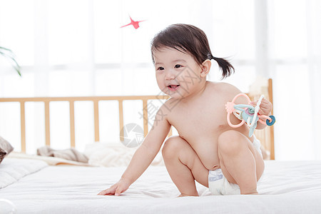12到18个月愉悦幼儿宝宝坐在床上玩耍背景图片
